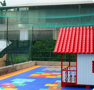 Área externa da ESTA com piso emborrachado colorido e casinha de brinquedo